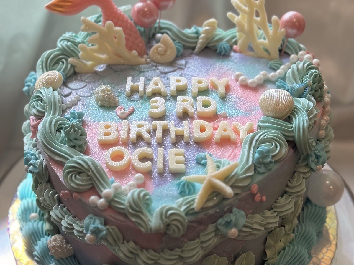 Mermaid under-the-sea birthday cake with pink and teal buttercream waves and chocolate seashells